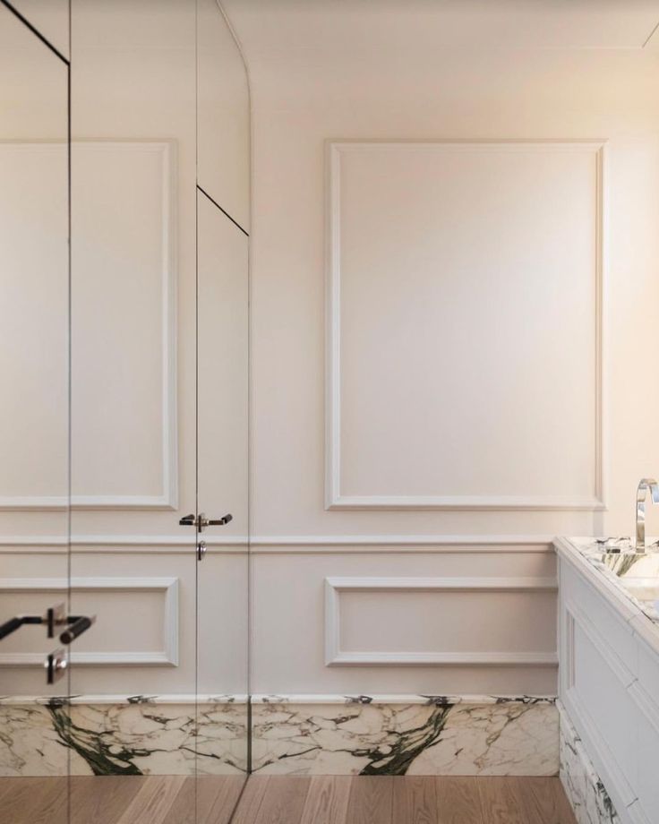 an empty bathroom with marble counter tops and white walls, along with wooden flooring