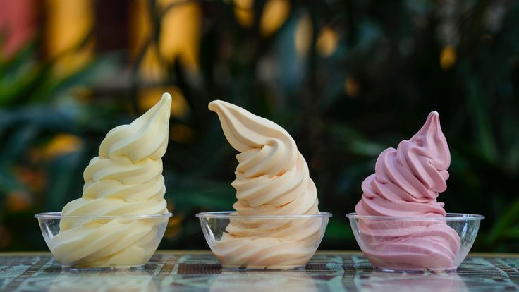 three different types of ice cream in small bowls on a table with plants behind them