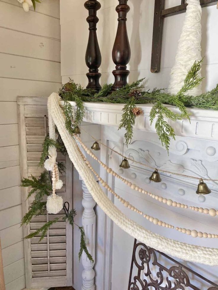 a mantel decorated for christmas with greenery and bells