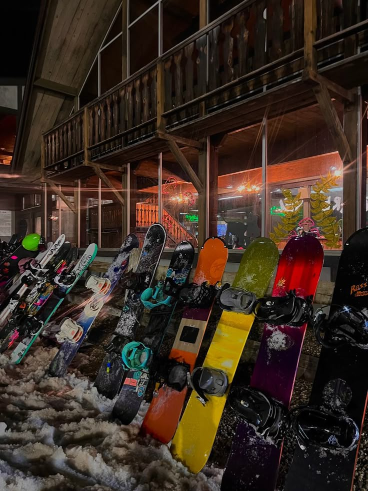 a bunch of snowboards are lined up in front of a building at night time