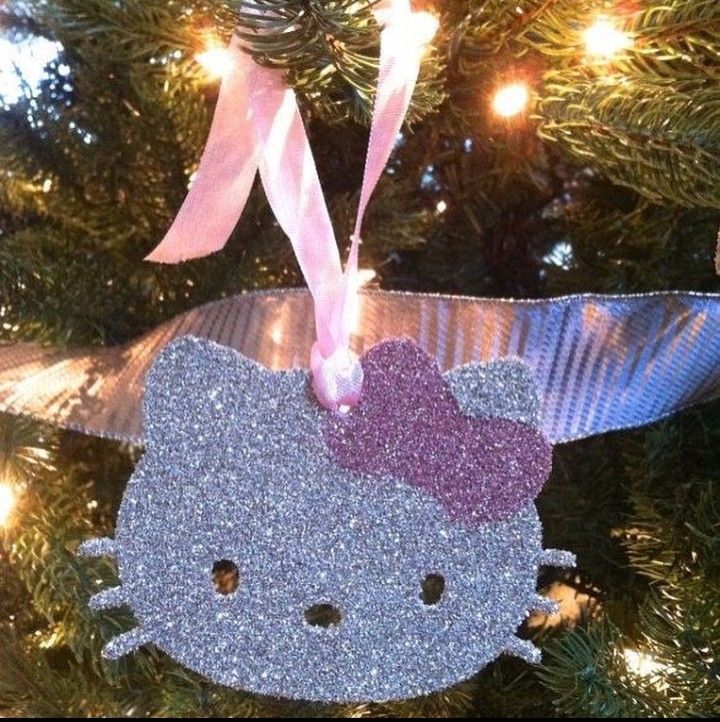 a hello kitty ornament hanging from a christmas tree with pink ribbon and lights