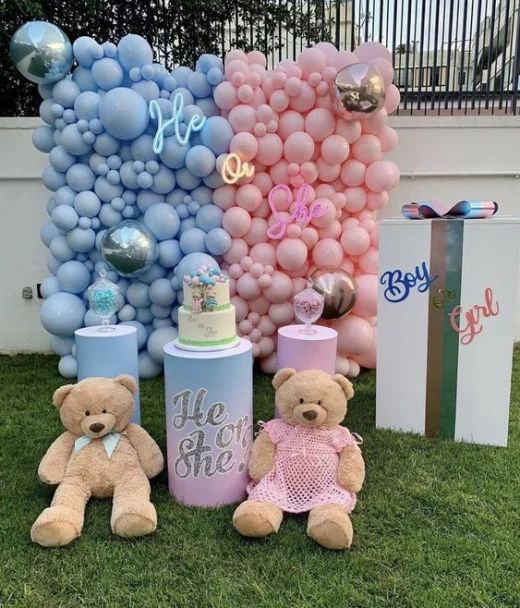 two teddy bears sitting in the grass next to some balloons and cake containers with letters on them