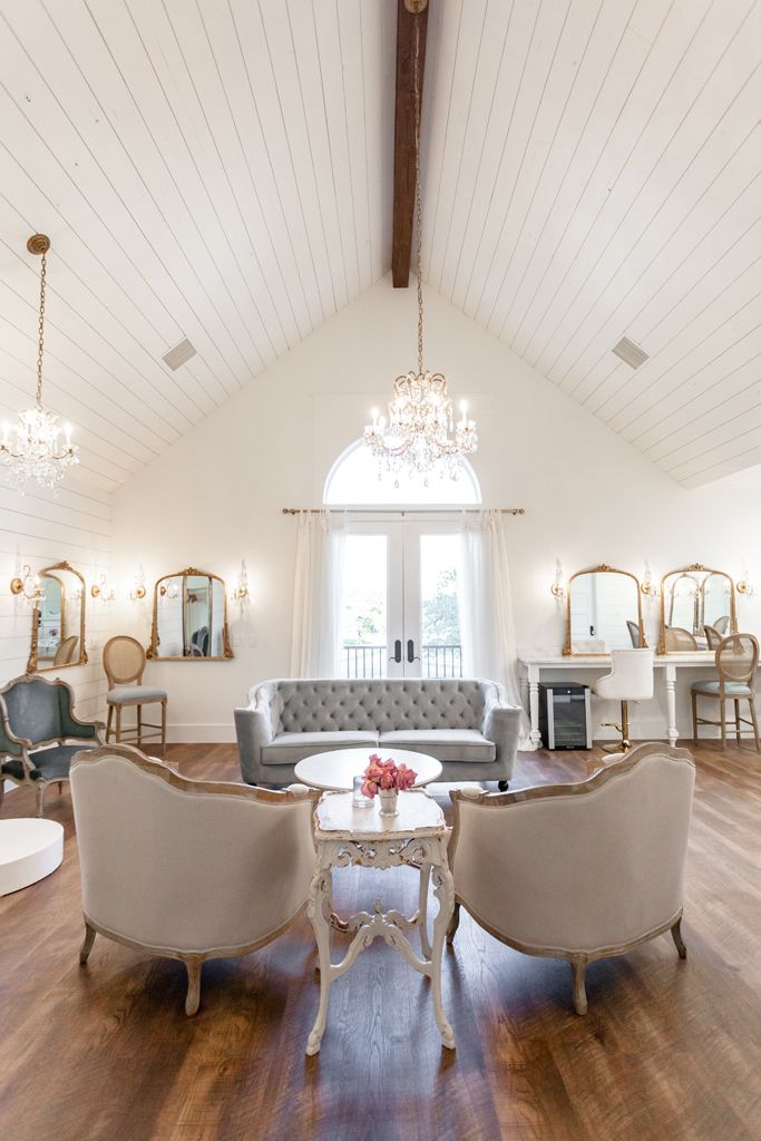 a living room filled with furniture and a chandelier hanging from the ceiling over a wooden floor