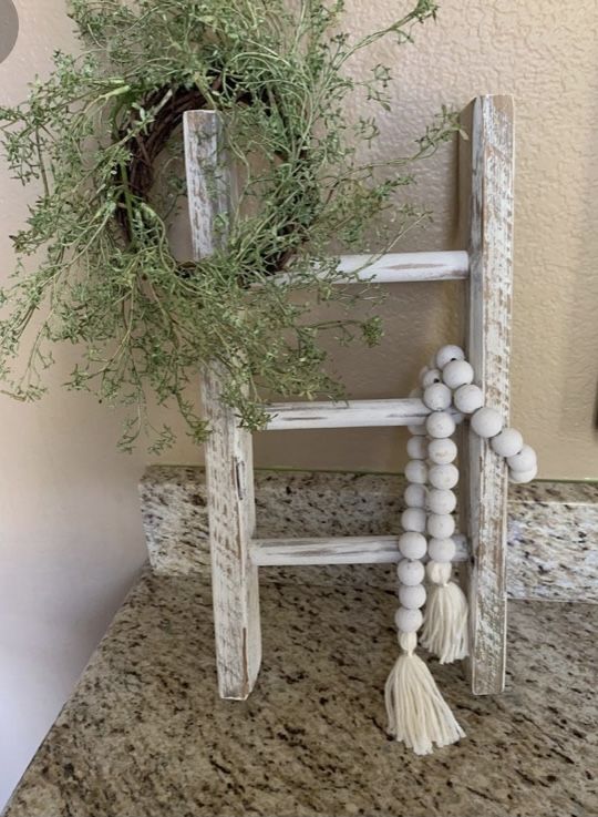 an old ladder is decorated with greenery and beads