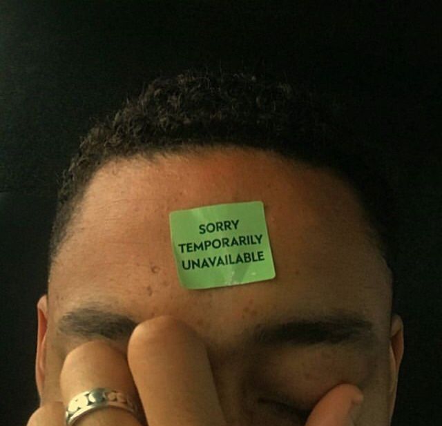 a man with a sticky note on his forehead covering his eyes and hand over his face