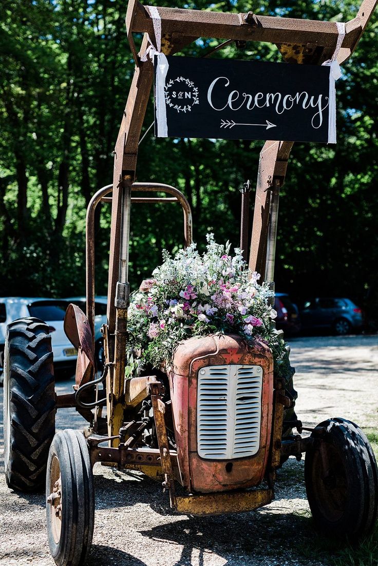 an old tractor is decorated with flowers and a sign