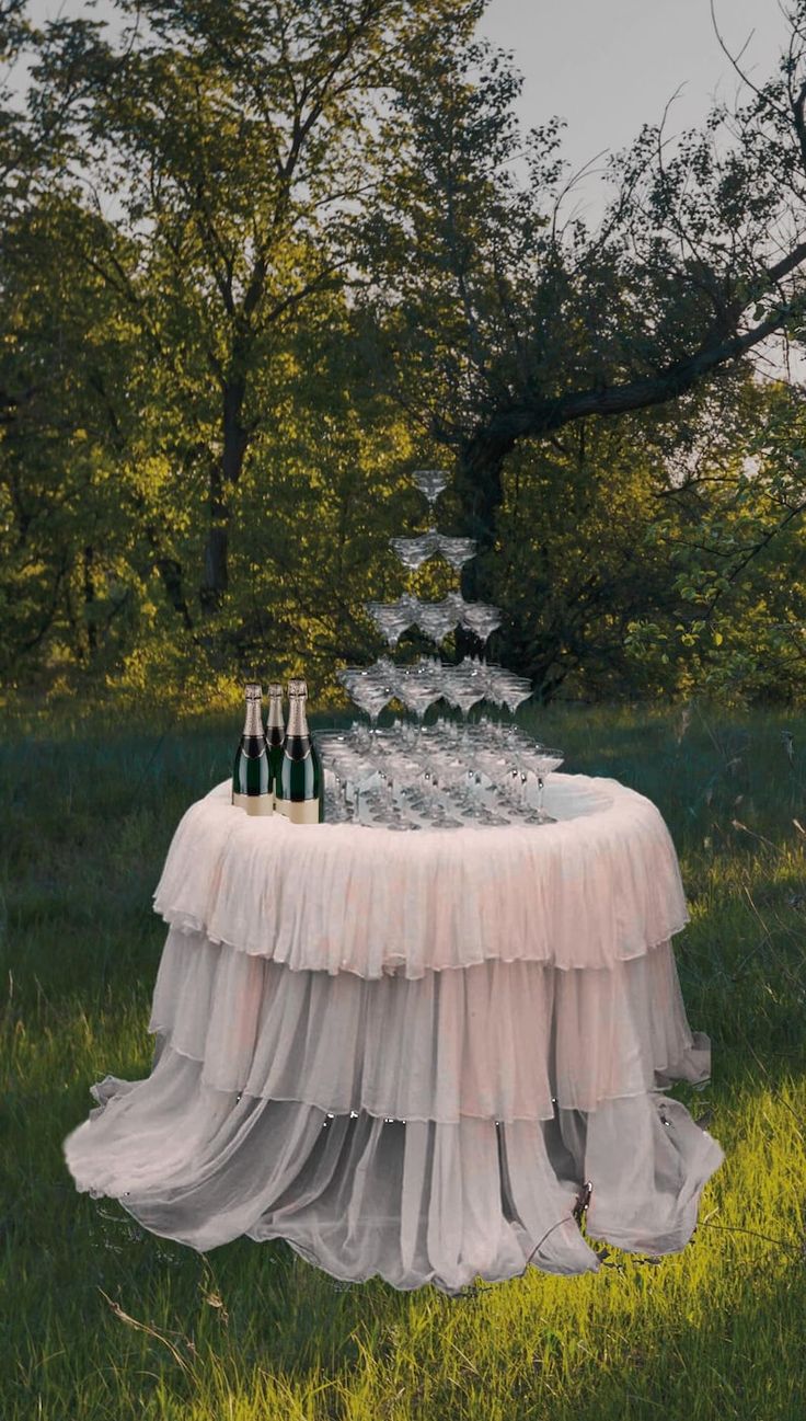 a table topped with bottles of wine and glasses on top of a lush green field