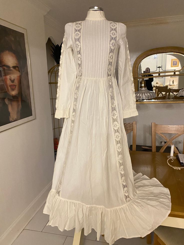 🕊Timeless beautiful white wedding dress by Laura Ashley 🕊Excellent condition with no flaws to note 🕊Pleated bodice and fits like a dream 🕊Measurements are vintage size 14 🕊18" pit to pit?>38"   🕊14" waist> 28"  🕊Hips free  🕊Cotton and beautiful lace trim details on the sleeves and bodice 🤍Button cuffs 🤍Concealed zipper at the back  🤍Long full flounce and flowing dress 🕊Look like an ethereal vampires wife in this showstopper of a timeless piece Cream Victorian Ball Gown For Wedding, White Victorian Dress With Fitted Bodice, Regency Style Wedding Gown With Lace Trim, Fitted Wedding Dress With Lace Trim For Bride, Fitted Lace Trim Wedding Dress For Bride, Victorian White Ball Gown Dress, White Victorian Ball Gown Dresses, Lace Victorian Dress With Fitted Bodice For Wedding, Victorian White Ball Gown