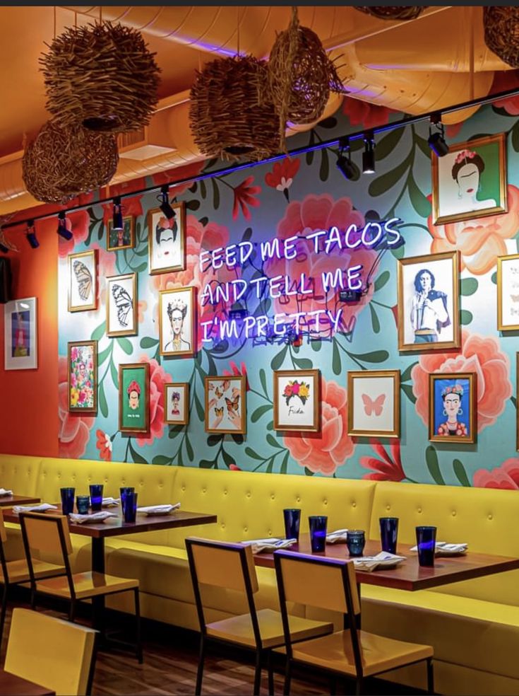 the interior of a restaurant with colorful wallpaper and pictures on the walls, along with yellow booths