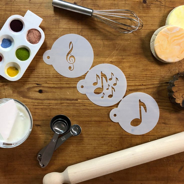 various crafting supplies on a wooden table including paint, cutters and music notes