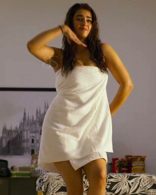 a woman in a white towel is standing on a bed and posing for the camera