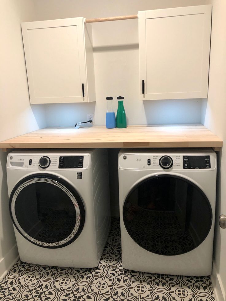 a washer and dryer in a small room with white cupboards on the wall