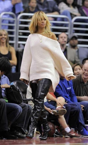 a woman in black leather pants and white sweater on a basketball court with people watching