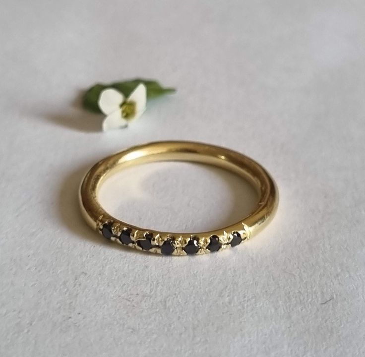 a close up of a ring on a white surface with a flower in the background