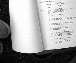 an open book sitting on top of a grass covered field next to a pair of shoes