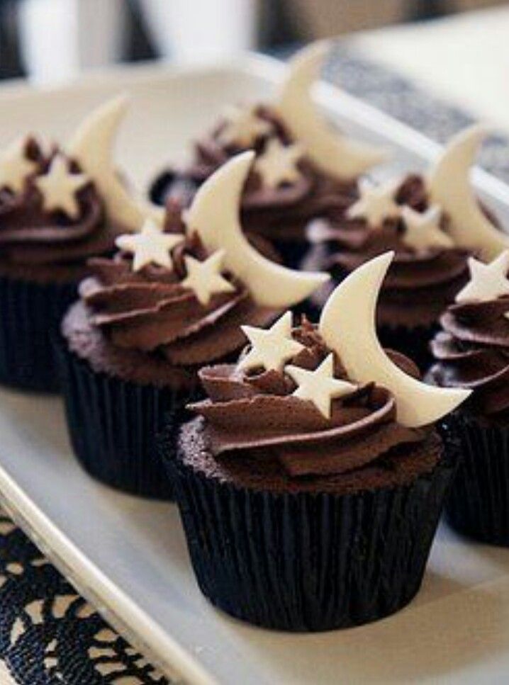 chocolate cupcakes decorated with white stars and crescent moon frosting on a plate