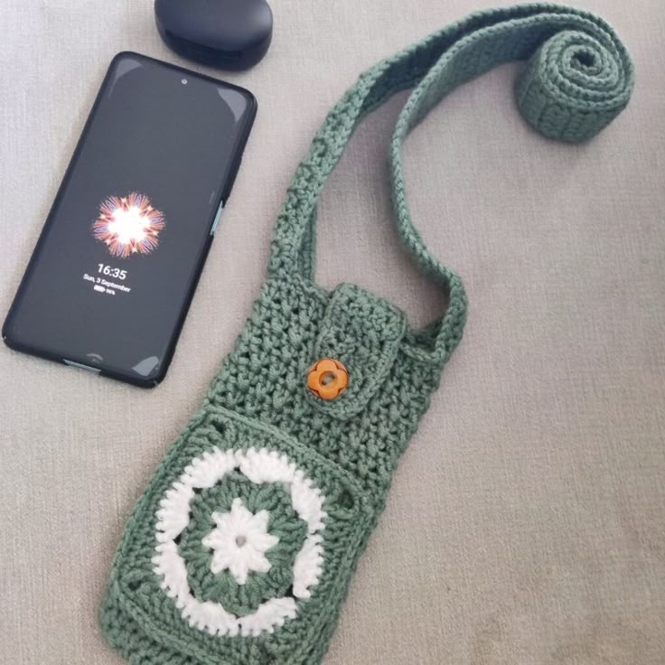 a cell phone is laying next to a crocheted bag and the case has an eyeball on it