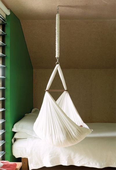 a white hammock hanging from the ceiling in a bedroom next to a bed