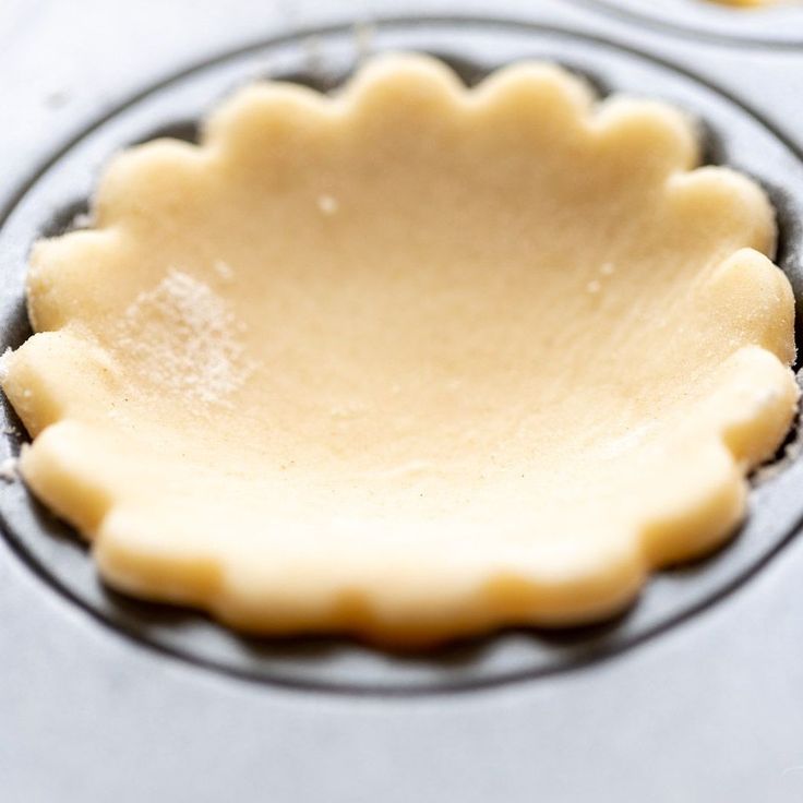 an uncooked pie crust in a muffin tin