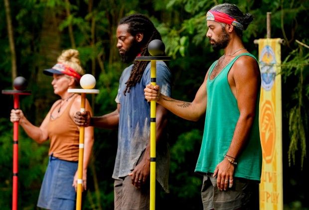 three men standing next to each other holding paddles and poles in front of trees