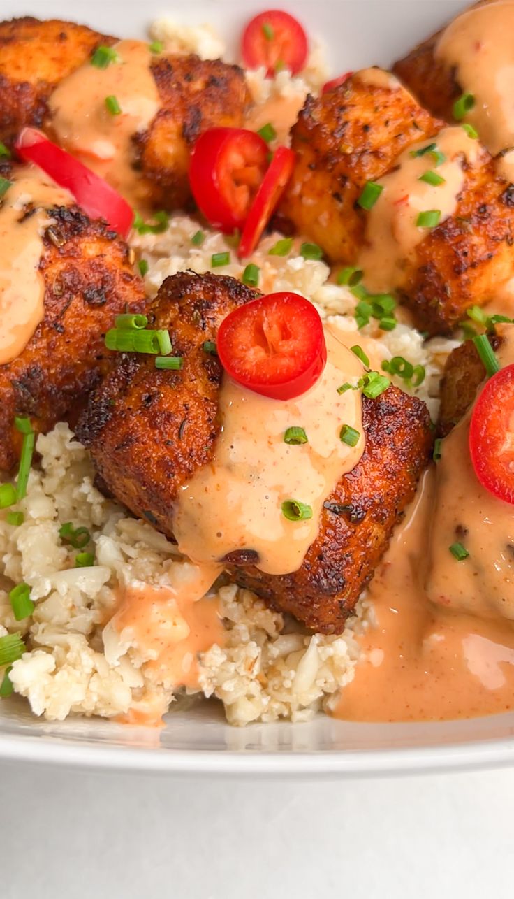 a white plate topped with meat and rice covered in gravy next to tomatoes