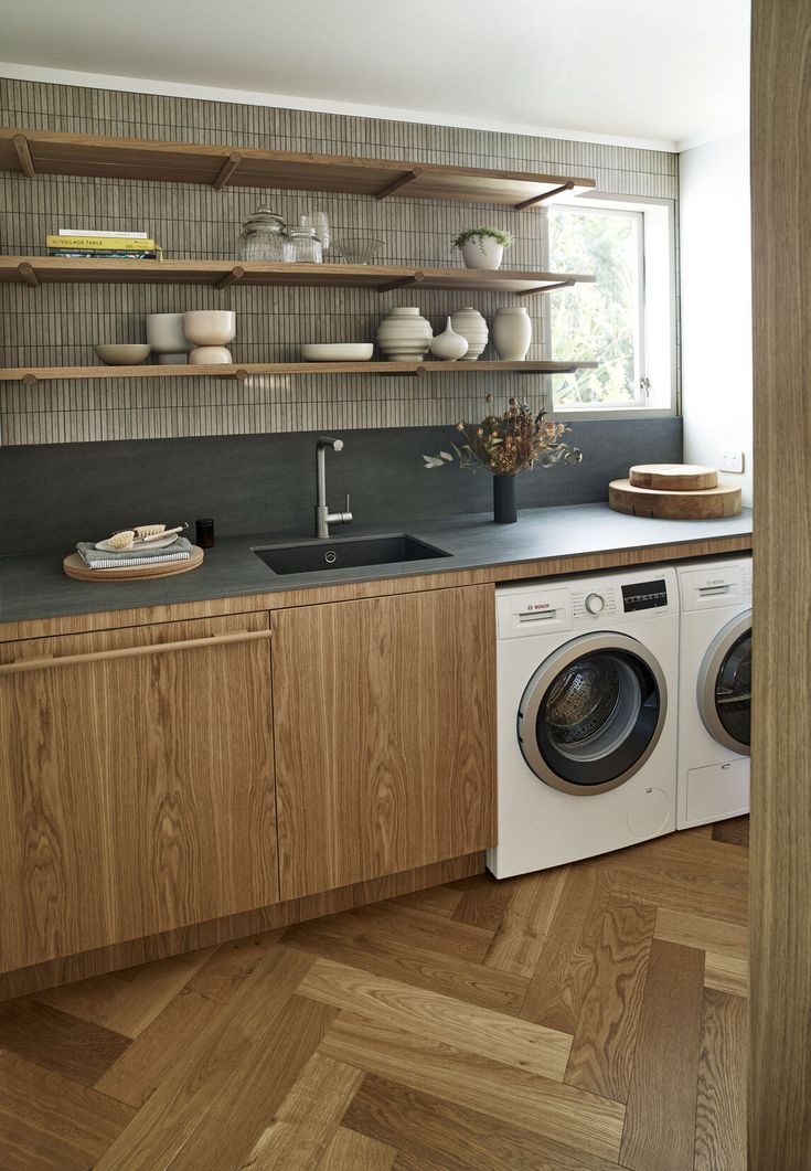 a washer and dryer in a kitchen with open shelves on the wall above