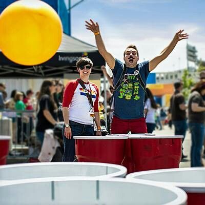 two men standing in front of large red buckets with their hands up and one man holding his arms wide open