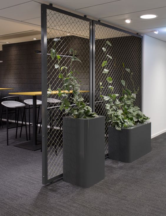 two planters with plants in them are next to each other near a table and chairs