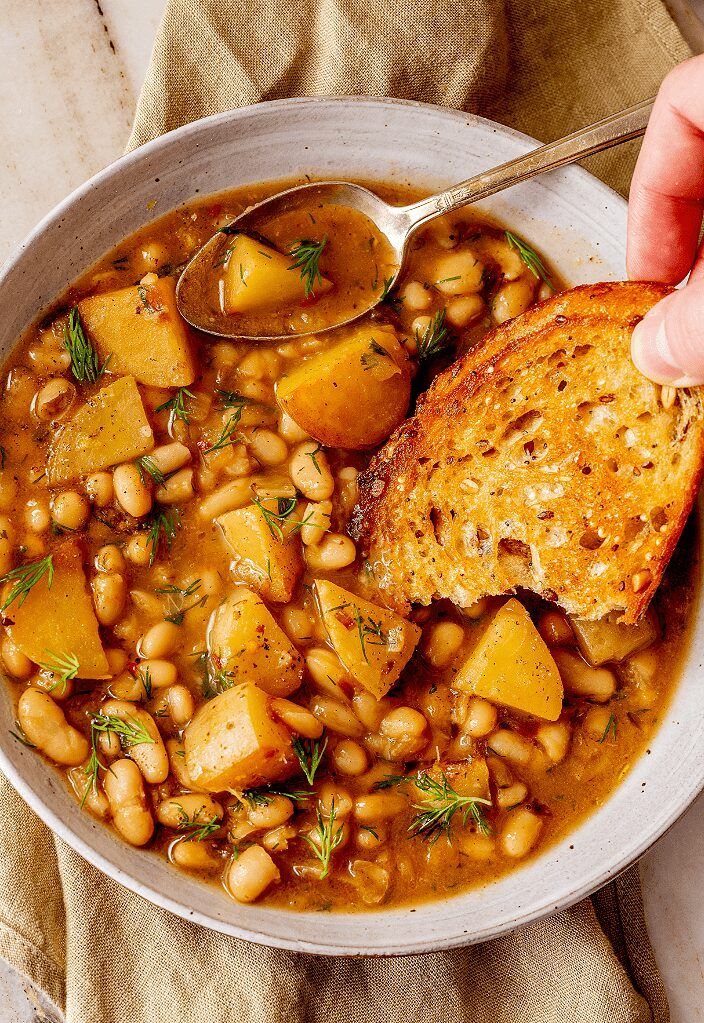 a bowl filled with beans and bread on top of a table