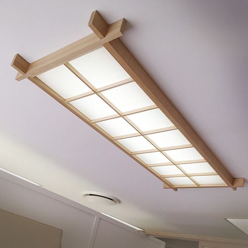 an overhead light fixture in a kitchen with white walls and wood trim on the ceiling