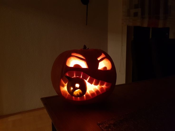 a pumpkin carved to look like a cat with its mouth open and eyes glowing in the dark