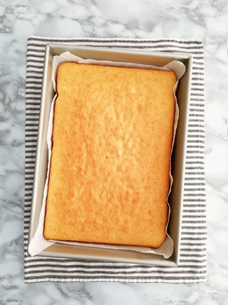 a square cake in a box on top of a marble countertop with black and white stripes