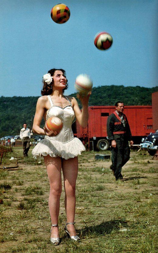 a woman in a white dress juggling balls