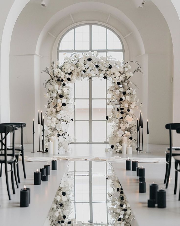 a wedding arch with flowers and candles in front of a large glass door that leads to an arched doorway