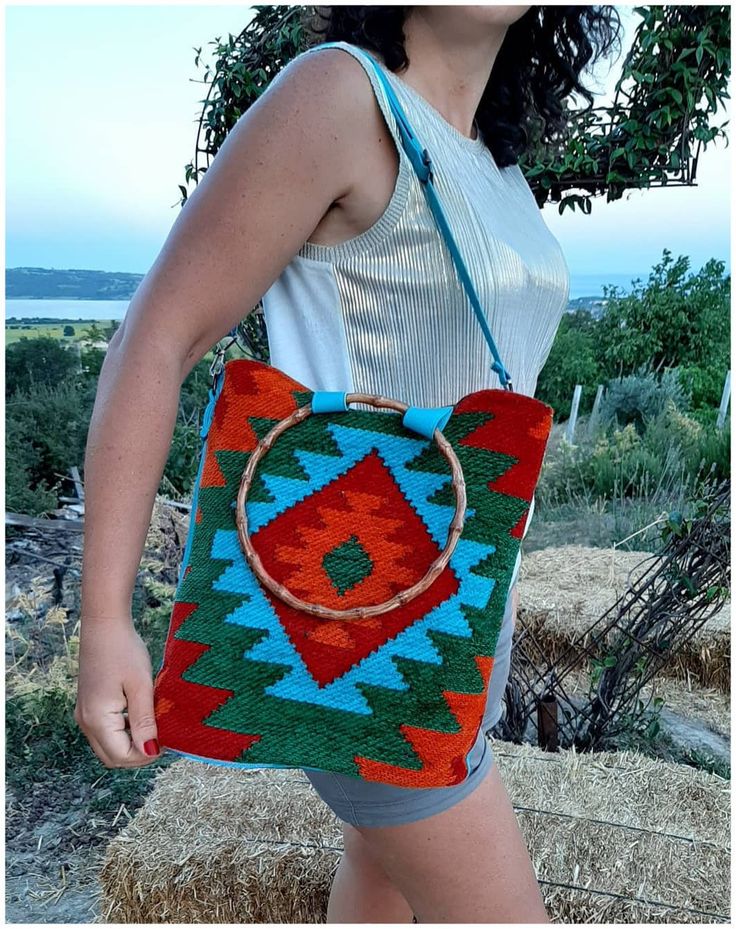 The vibrant colors and unique ethnic patterns on this carry-all bag make it a practical and fashionable accessory. Made from durable kilim - carpet - rug fabric, this day bag is great when you are out and about. Treat yourself, or give as a gift. With a geometric pattern and cute bamboo shape handles, It can be carried as a tote or worn over the shoulder or crossbody, with the adjustable strap making it really practical as well as stylish. wool and cotton mix kilim fabric, We use and also an inn Bohemian Tote Bag With Bamboo Handle, Bohemian Bags With Round Handle For Daily Use, Bohemian Shoulder Bag With Round Handle, Multicolor Rectangular Shoulder Bag With Bamboo Handle, Bohemian Travel Bag With Round Handle, Bohemian Turquoise Rectangular Shoulder Bag, Green Bohemian Handheld Bag, Multicolor Tote Shoulder Bag With Bamboo Handle, Bohemian Brown Shoulder Bag With Round Handle