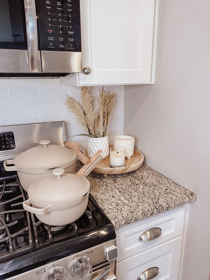 a stove top oven sitting under a microwave next to a pot and pan filled with food