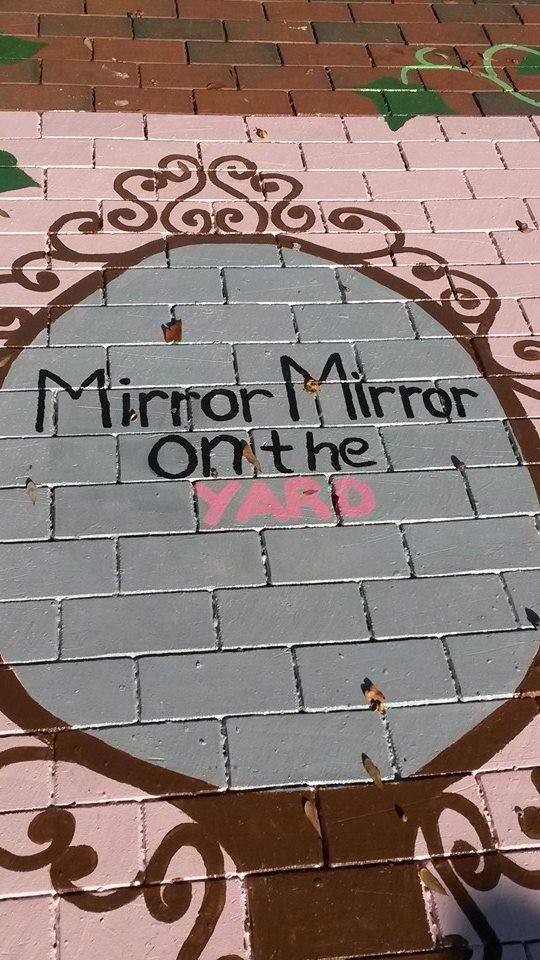 a brick sidewalk with the words mirror mirror on the wall written in pink and black