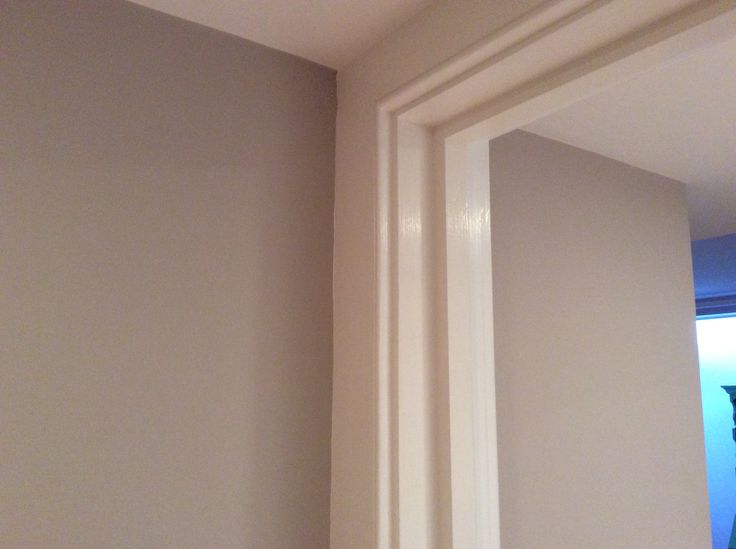 the corner of a room with a mirror and white trim on it's wall