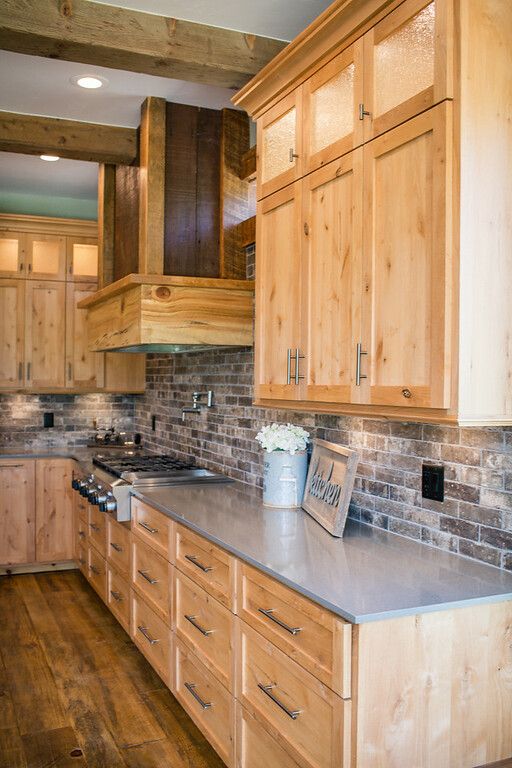 a large kitchen with wooden cabinets and stainless steel counter tops, along with wood flooring