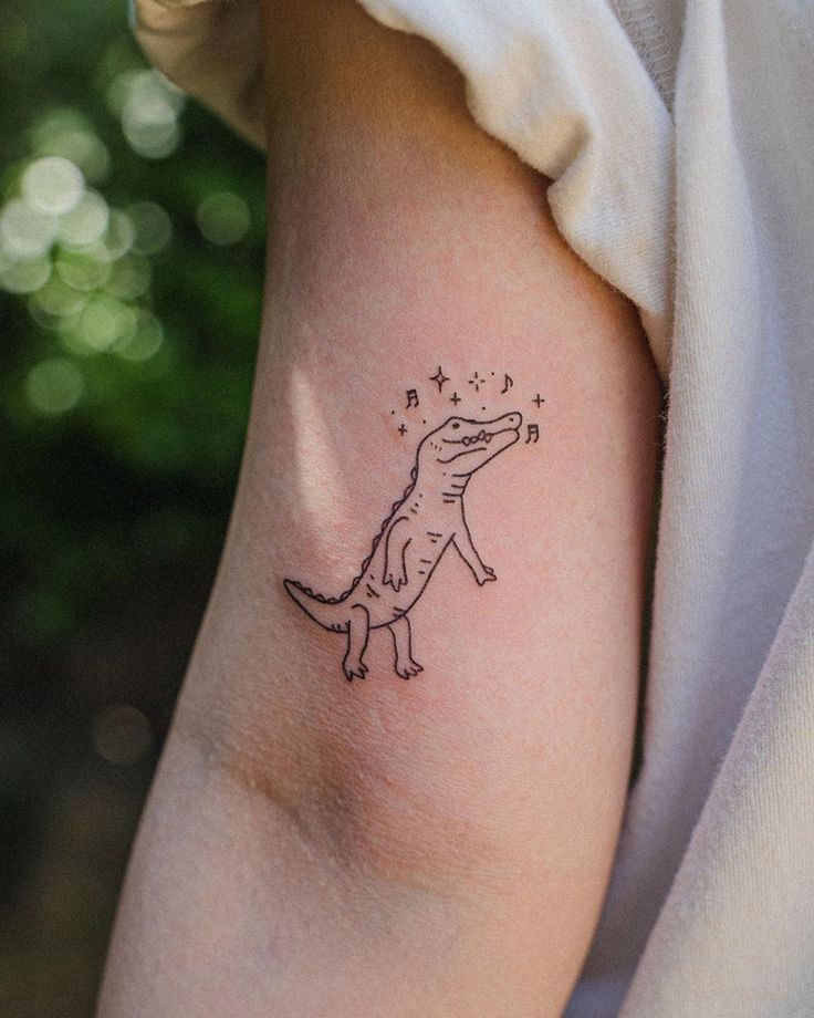 a small dinosaur tattoo on the arm