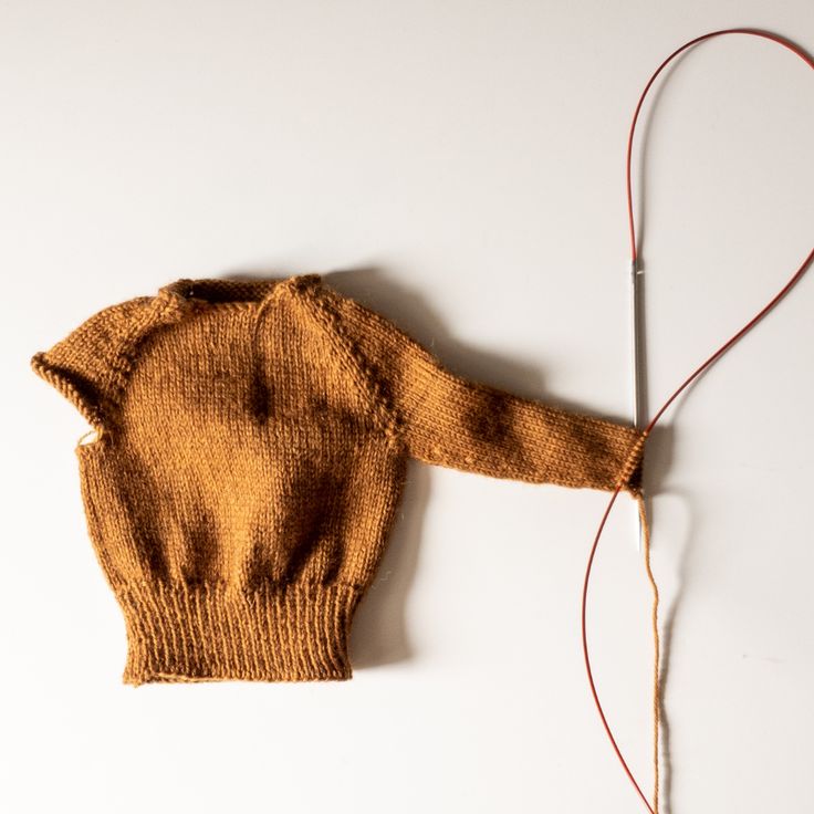 an old sweater is hooked up to a cord on a white surface with a pair of scissors