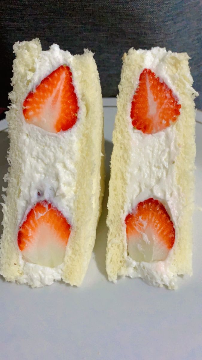 two slices of cake with white frosting and strawberries on top