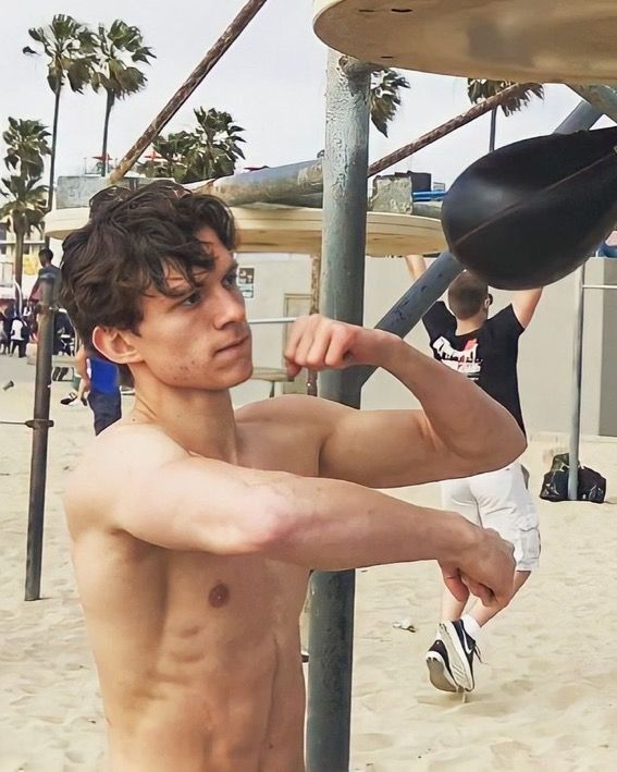 a shirtless young man is playing on the beach