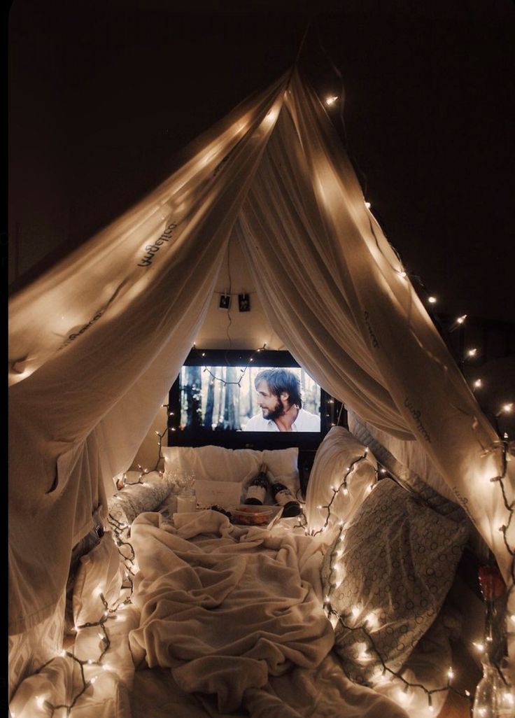 a bed covered in white sheets and lights