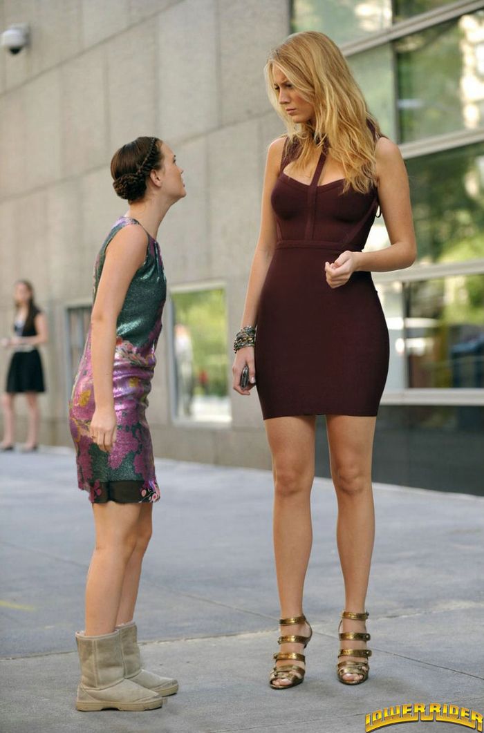 two beautiful women standing next to each other on the sidewalk in front of a building