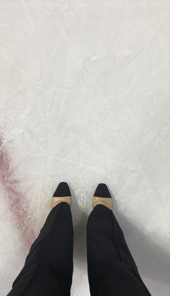 the legs and feet of a person who is standing on an ice rink