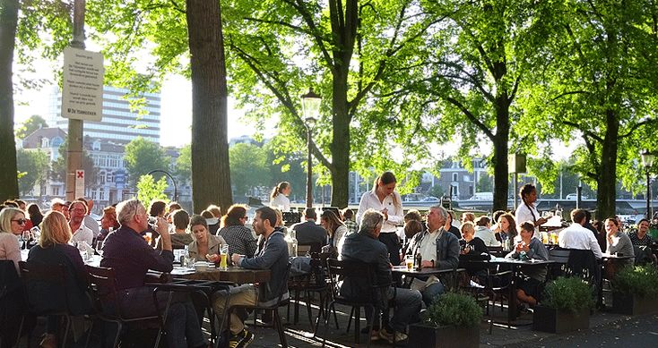 many people are sitting at tables in the park