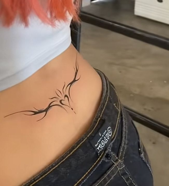 a woman's stomach with a bird tattoo on her lower back and the bottom part of her body