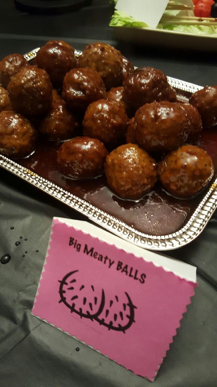 some meatballs are sitting on a metal tray with a pink sign next to it