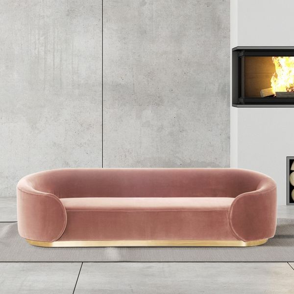 a living room with a pink couch and fireplace in the back ground, surrounded by concrete walls